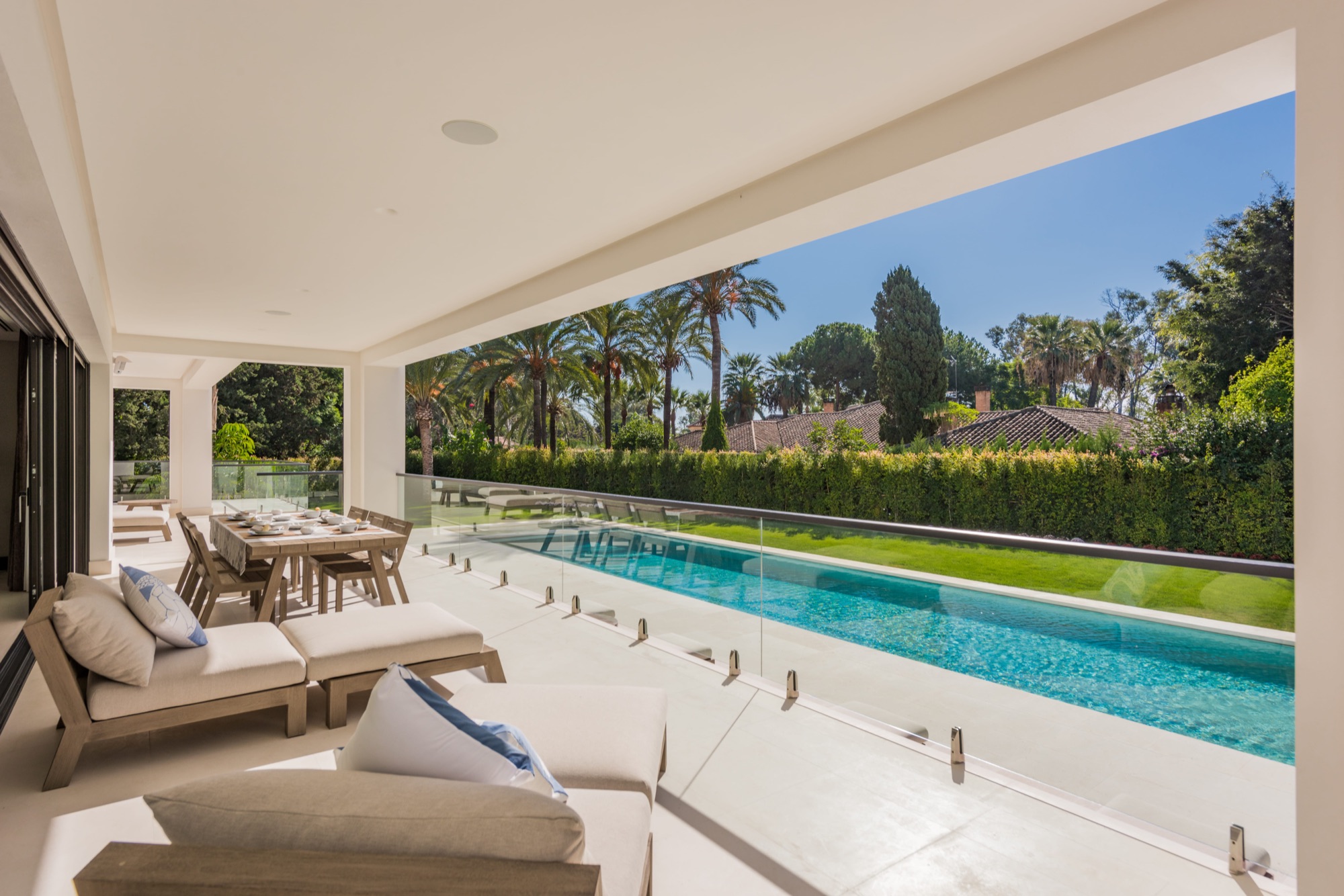 Terraza de lujo con barandilla de vidrio y piscina en Marbella